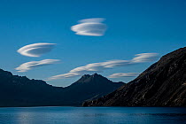 Lenticular clouds in a blue sky over mountains, South Georgia Island, South Atlantic.