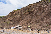 Abandoned boat caught in mudslide caused by tidal erosion of Thurstaston cliffs after a long period of heavy rain, River Dee Estuary, Wirral, Merseyside, UK. May, 2021.