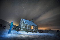 Cross country skier outside Ryvoan Bothy at night, Abernethy National Nature Reserve, Cairngorms National Park, Scotland, UK. January, 2021.