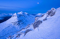 View of snow-covered Liathach mountain by moonlight from Beinn Eighe summit, Torridon, Highlands, Scotland, UK. January, 2021.