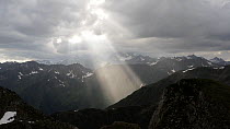 Aerial tracking shot of a sun beam breaking through the clouds on a mountain landscape, Gsiesertal, South Tyrol, Italy, June.