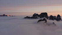 Aerial tracking shot of the Dolomite Mountains above the clouds at Sunrise, Lagazuoi, Cortina D'ampezzo, Italy, April.