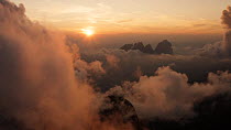 Aerial tracking shot revealing the Dolomite Mountain range through the cloud and fog at sunset, Passo Fedaia, Marmolada, Italy, July.