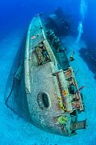 RF - Scuba diver swimming alongside the bow of the Kittiwake shipwreck on the seabed, Seven Mile Beach, Grand Cayman, Cayman Islands, Caribbean Sea. (This image may be licensed either as rights manage...