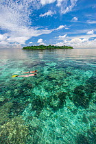 Snorkelers  swimming over reef on particularly calm glassy day off Sipidan Island, Malaysia. Cebeles Sea, Western Pacific Ocean. Model released