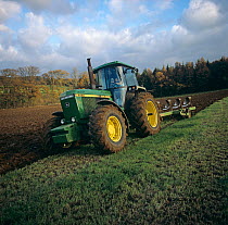 Tractor and large reversible coulter plough ploughing old grassland for replanting, Berkshire, UK. November.