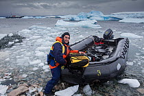 Photographer, Franco Banfi, unloading his waterproof camera bag from boat for a land excursion, Antarctic Peninsula, Antarctica.