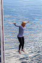 Woman taking the 'Polar plunge' from the side of a  cruise ship. Polar plunging is a popular activity with cruise ship visitors to the polar regions, Prospect Point, Antarctic Peninsula, Ant...