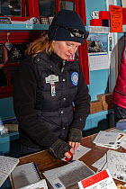 Post office worker stamping mail at Port Lockroy Post Office, the most southerly Royal Mail post office, Port Lockroy, Goudier Island, Antarctic Peninsula, Antarctica.