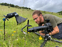 Photographer, Alex Hyde, at work in the field photographing invertebrates with macro set up, UK. June.