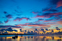 The sky lights up at dawn with boats floating on still waters off the island of Yap, Micronesia, Pacific Ocean.
