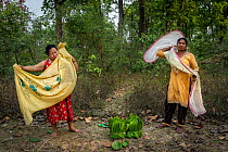 Two women with bundles of Sal leaves they have collected from the community forest; the leaves will be used to make bowls to eat from. Each villager is allowed to take an allotment of resources from t...