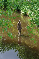 Cast iron figure by sculptor Anthony Gormley from his series called "6 Times", located along Water of Leith, Edinburgh, Scotland, UK. June. Editorial use only