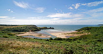 Three Cliffs Bay with Pennard Pill stream flowing across the beach at mid tide, Penmaen, Gower Peninsula, Wales, UK. July, 2021.
