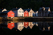 Colourful wooden houses reflecting in water of Laerdalsfjorden at night, Laerdalsoyri, Norway. May, 2019.