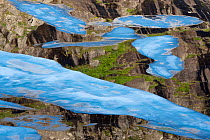Floating ice sheets on the surface of Ovre Pikhaugvatnet lake, with reflection of mountainside. Glomdalen valley, Saltfjellet-Svartisen National Park, Norway. August, 2015.