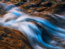 Water flowing over marble riverbed in late evening sunlight, Lahko National Park, Norway. July.
