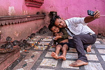 Man and boy sitting on ground taking photograph with mobile phone surrounded by Black rats (Rattus rattus) feeding, Karni Mata Temple (The Temple of Rats), a Hindu temple dedicated to the Hindu Goddes...