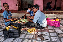 Black rats (Rattus rattus) climbing over crates of produce with three men sitting on floor preparing food, Karni Mata Temple (The Temple of Rats), a Hindu temple dedicated to the Hindu Goddess Karni M...