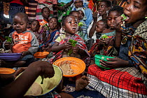 Women and children sitting together to eat high nutrition porridge. The porridge is fed to the children to improve their nutritional intake and is specially formulated to provide key nutrients many ar...