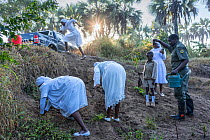 Gorongosa head warden planting trees with his family along the river edge to help prevent erosion. All the women in the family wear white at all times - part of their culture as a Christian sect, Goro...