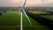 Aerial tracking shot around moving wind turbines in autumn, Devon, UK.