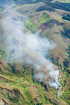 Aerial view of deforestation, plume of smoke from forest burning, fragmentation and land slides (lavaka), Central Highlands, Madagascar. April 2008.