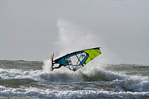 Windsurfer in rough seas off the coast of Rhosneigr, Anglesey, Wales, Irish Sea UK. October, 2022.