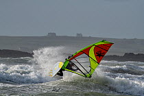 Windsurfer in rough seas off the coast of Rhosneigr, Anglesey, Wales, Irish Sea UK. October, 2022.