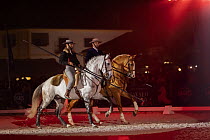 Two pompilho (Portuguese cowboys), riding  Lusitano horses and  demonstrating skills with garrochas, Feira da Golega, Ribatejo, Portugal. Garrochas are long poles used to move cows.