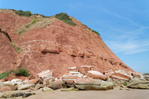 Eroded, collapsing red sandstone coastal cliffs and fallen rocks between Orcombe Point and Sandy Bay, Exmouth, Devon, UK. August, 2022.