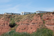 Holiday park static caravans perched on red sandstone cliff tops above Sandy Bay Beach, Exmouth, Devon, UK. August, 2022.