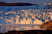 Tourists in front of Eqi glacier at sunset, Disko Bay, Greenland, August, 2022.