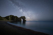 Durdle Door backlit at night under the Milky Way, Jurassic Coast, Dorset, England, UK. April, 2021.