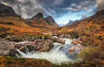 River Coe flowing over rocks with the peaks of the Three Sisters of Glencoe in background, Scottish Highlands, Scotland, UK. October, 2020.