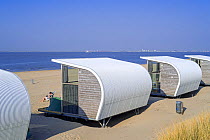 Row of modern beach houses along on sandy beach looking out to sea on a sunny day, Groede, Zeeland, The Netherlands, North Sea. May, 2022.