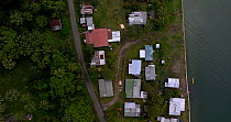 Aerial tracking shot of coastal community. The village protects itself from rising sea levels with a concrete seawall. Coral Coast, Viti Levu, Fiji.