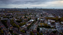 Aerial tracking shot of houses, roads and cranes, North London, UK. November.
