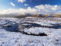 Upland peat bog on Fairfield fell covered in snow in winter, looking towards Langdale, Lake District, Cumbria, UK. January, 2022.