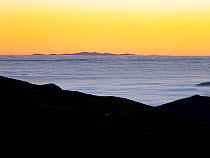 Sunset view looking towards the Isle of Man over Harter Fell from the Coniston fells with mist from a temperature inversion, Lake District, Cumbria, UK. December, 2021.