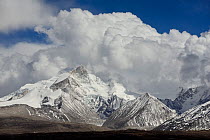 View of Gangdise snow-capped summits, mountain range parallel to Himalayas, in clouds.  Tibetan Highlands, China. May, 2016.