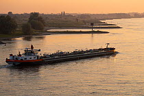 Barge traffic on the River Rhine at dawn, Nijmegen, The Netherlands. June.