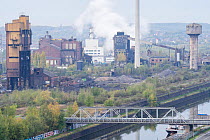 View of old and new industrial buildings, steel mills, gas plants and hydrogen gas plants, along the polluted Sambre river, Charleroi, Belgium. October, 2022.