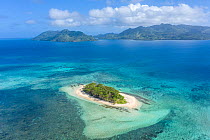 Aerial view of small island surrounded by coral reefs with Beqa island, south of Viti Levu, visible in the distance, Fiji, Pacific Ocean. August, 2020.