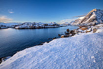 Snow over shore and mountains in winter, Henningvaer, Lofoten Islands, Norway. March, 2023.