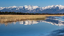 Mouth of the Bolshoy Chivyrkui River with snow-covered mountains in background, Lake Baikal, Siberia, Russia. October, 2021.