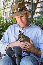 Wildlife guide holding orphaned Tammar wallaby  (Macropus eugenii) joey, Kangaroo Island, Australia. October, 2015.