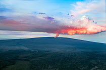 Mauna Loa Volcano erupting, sending up a plume of toxic volcanic gases, illuminated by the flowing lava at dawn, Big Island, Hawaii, USA. November, 2022.