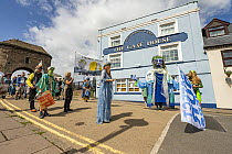 Goddess of the Wye puppet procession walking through street in Monmouth, part of the Save the Wye Campaign to raise awareness of pollution levels in the River Wye, Monmouth, Wales, UK, 9th July, 2023.