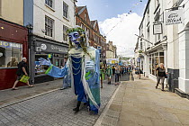 Goddess of the Wye puppet procession walking through street in Monmouth, part of the Save the Wye Campaign to raise awareness of pollution levels in the River Wye, Monmouth, Wales, UK, 9th July, 2023.